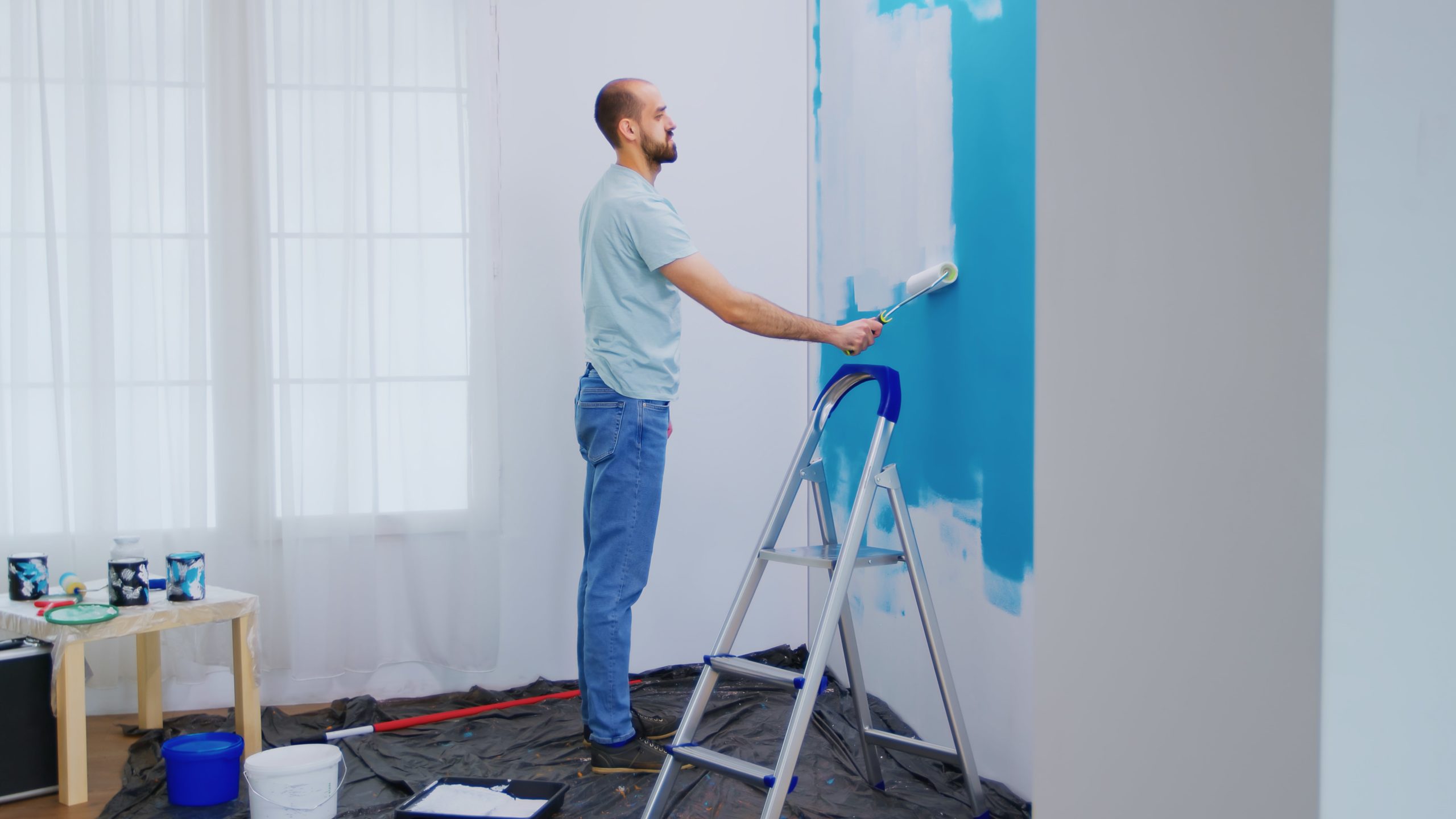 handyman-painting-wall-with-roller-brush-dipped-white-paint-handyman-renovating-apartment-redecoration-home-construction-while-renovating-improving-repair-decorating-min